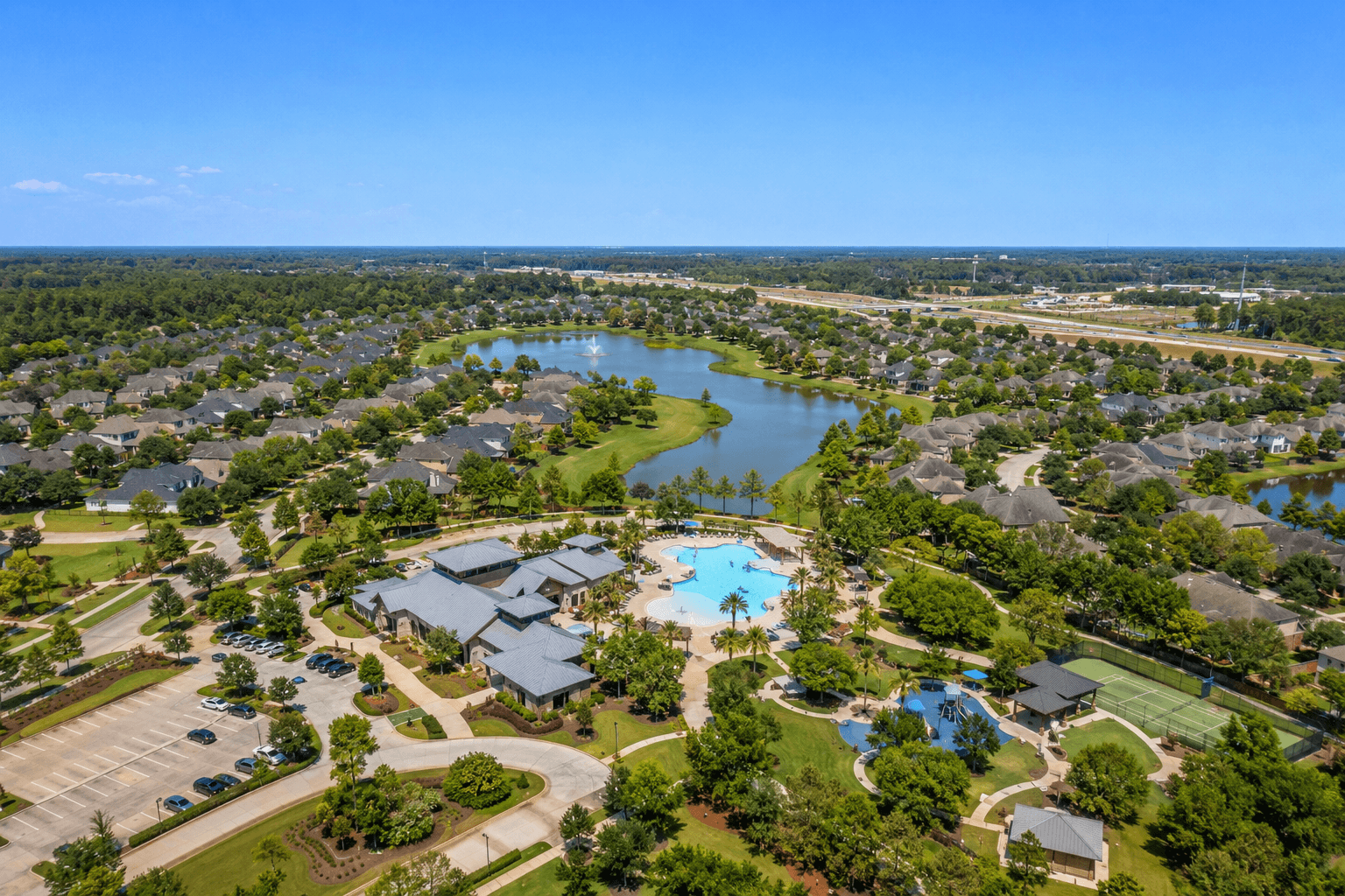 Aerial view of Grand Central Park master-planned community in Conroe Texas with resort pool, lake, and mature landscaping