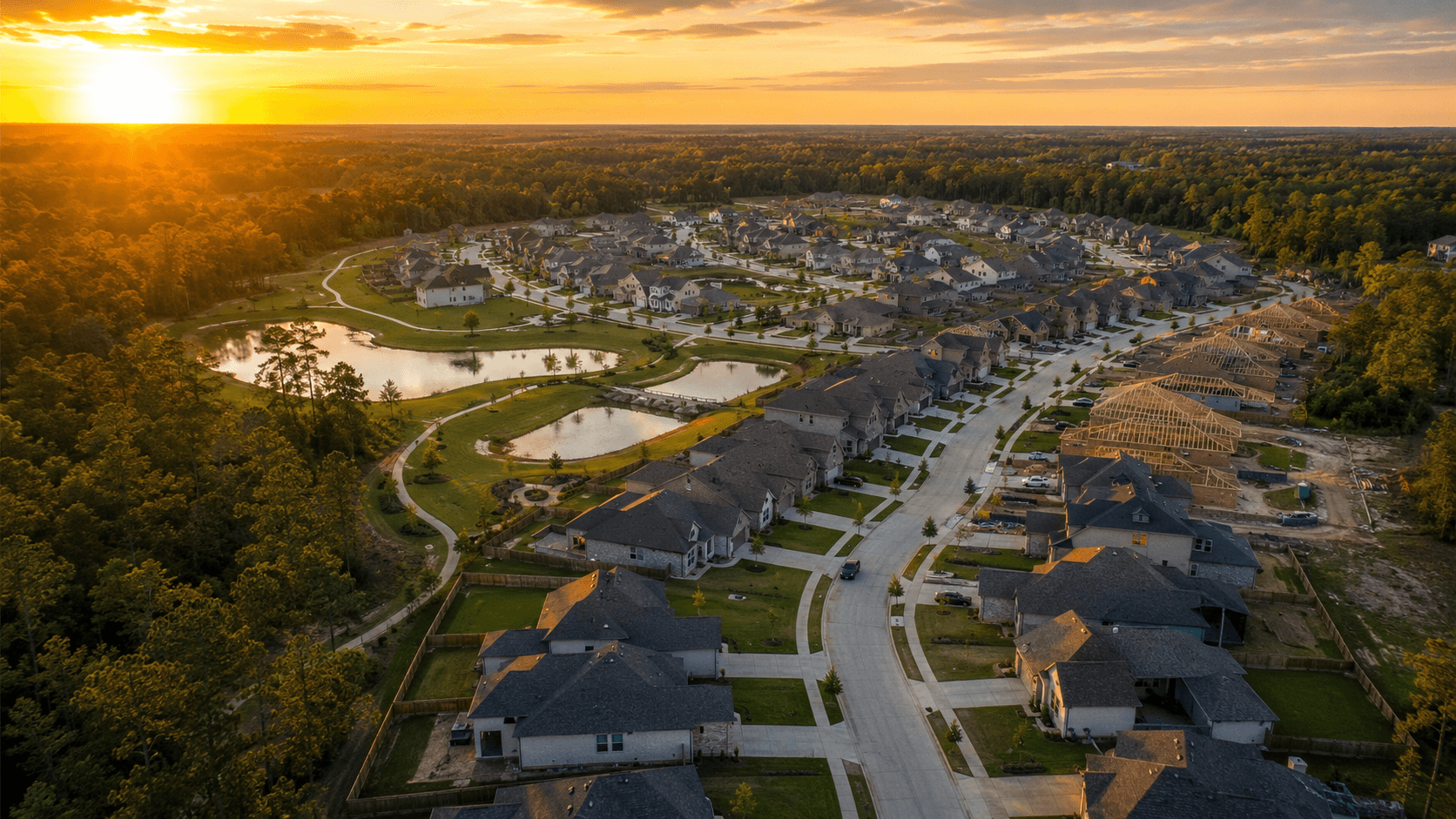 Aerial view of Mostyn Springs new construction community in Magnolia TX at sunrise with pond and homes under construction