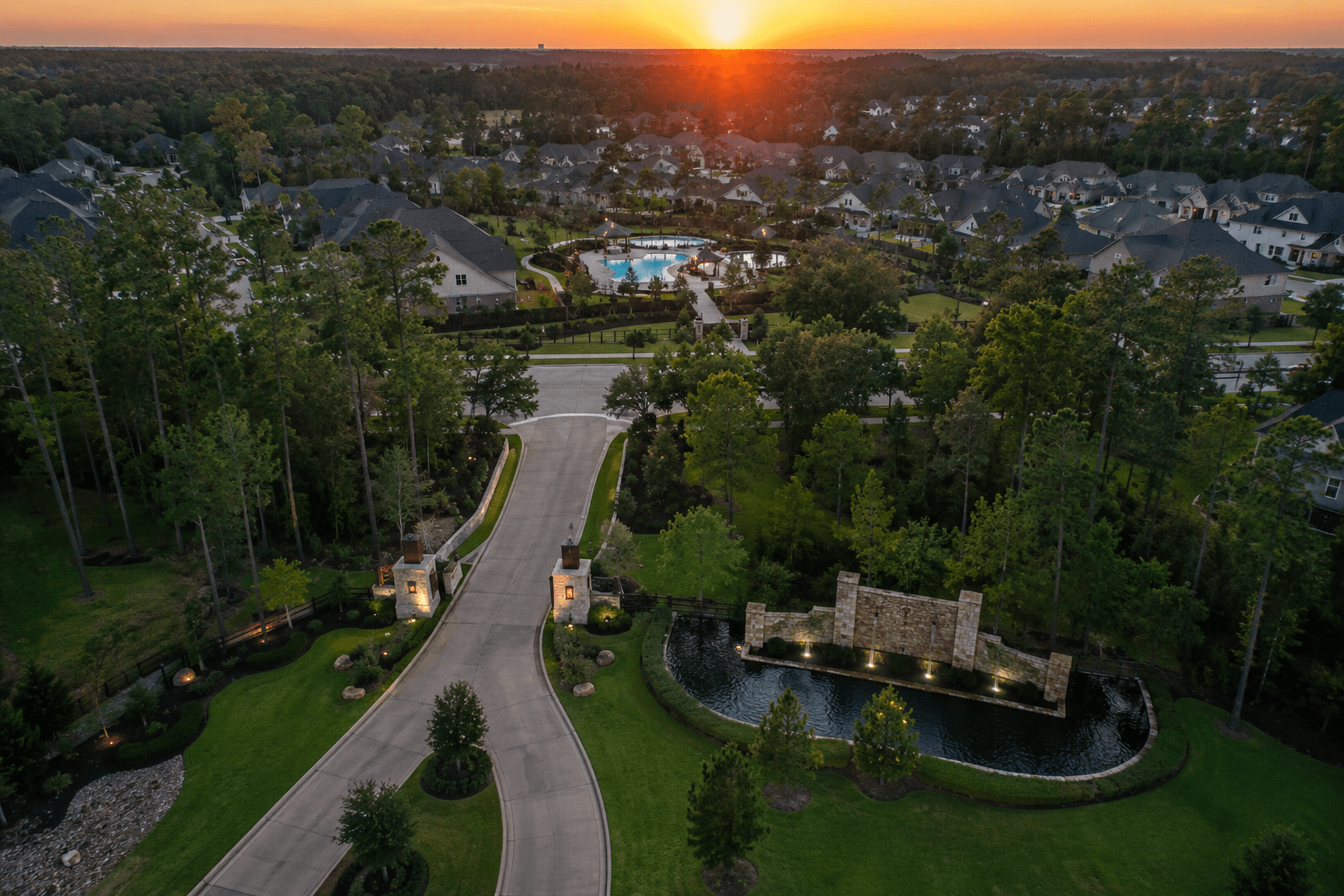 Aerial view of a North Houston master-planned community with tree-lined streets and a resort-style pool at sunset