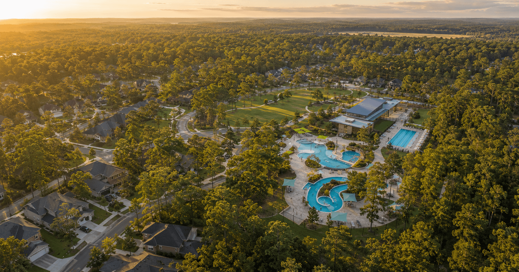 Aerial view of The Woodlands Hills community in Willis Texas with resort pool complex and homes nestled among pine trees at sunset